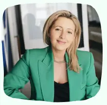 Smiling professional woman in a green jacket, embodying expertise and approachability in mental health support